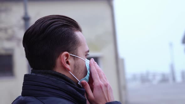 Serious Man Puts on Blue Medical Mask Among Rotating City