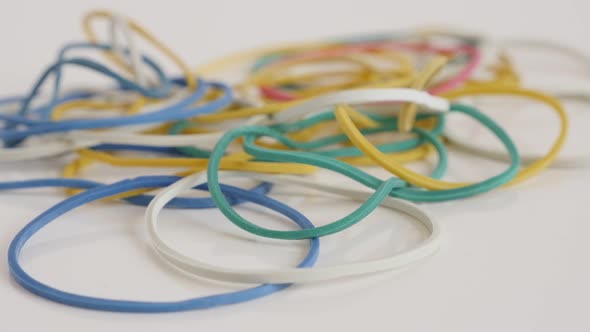 Colorful loops of rubber on white slow tilt 4K footage