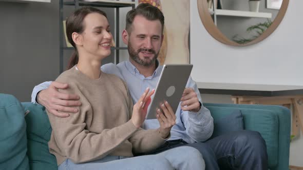 Couple Using Tablet While Sitting on Sofa