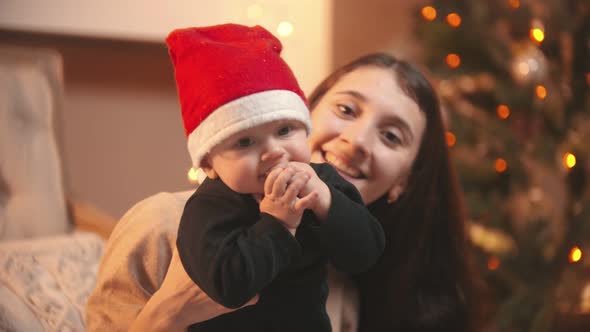 A Young Smiling Woman Holding Her Baby in Christmas Studio