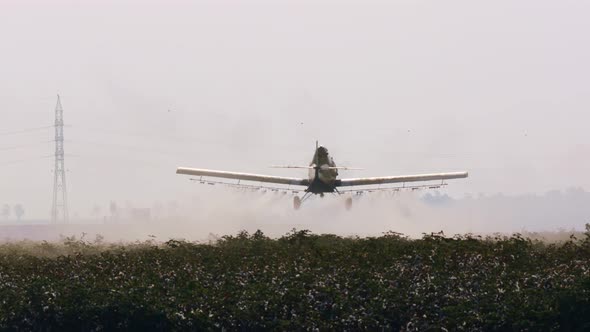 Crop duster spraying chemicals over a cotton field - slow motion