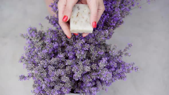 Top View of Lavender Lying on Table with Female Young Hands Showing Natural Soap