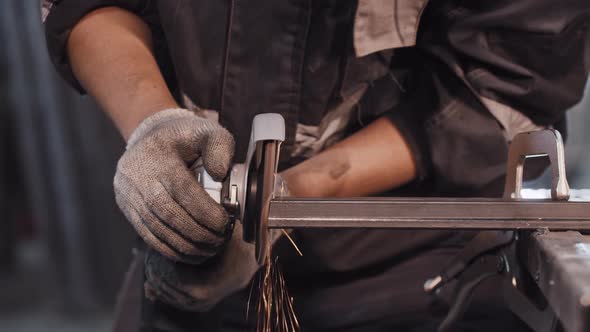 Young Man Working at the Construction Plant  Grinding the Angle Cut on the Metal Detail