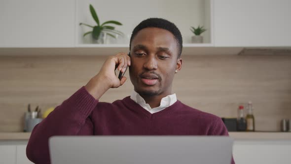 Sales Manager is Having a Conversation on a Phone in Front of a Laptop From His Living Room Distant