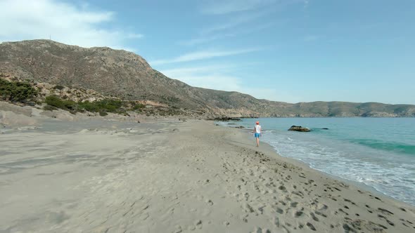 Beach travel - woman walking on sand Kedrodasos beach, Greece. FPV drone.