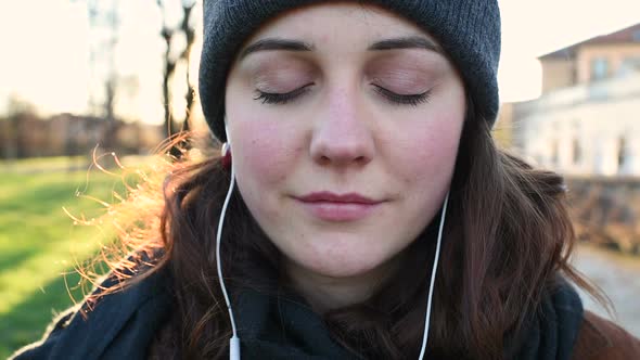 Slow motion portrait young beautiful woman outdoor eyes closed listening music toothy smile