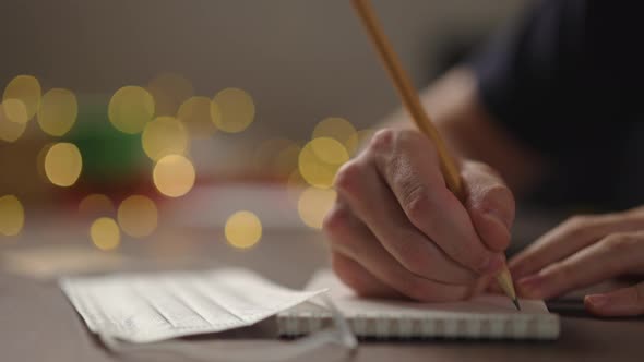 Slow Motion Closeup Man Writes Shopping List Notepad Pencil Under Warm Light Evening Medicine Mask