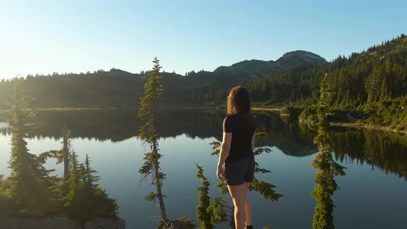 Girl Standing on Tree Stump Looking Out Over Scenic Lake