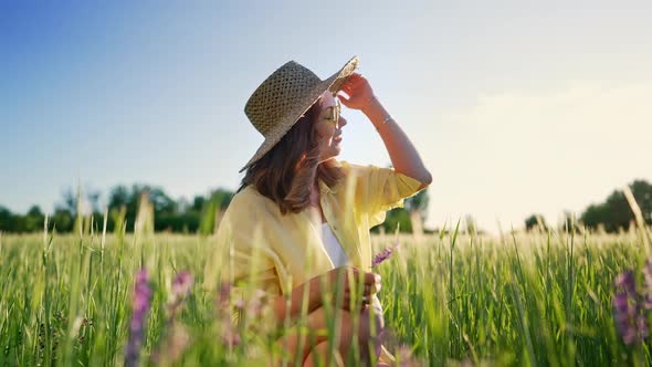 Portrait of Rural Stylish Woman in Straw Hat and Eyewear Posing in Fresh Wheat Field