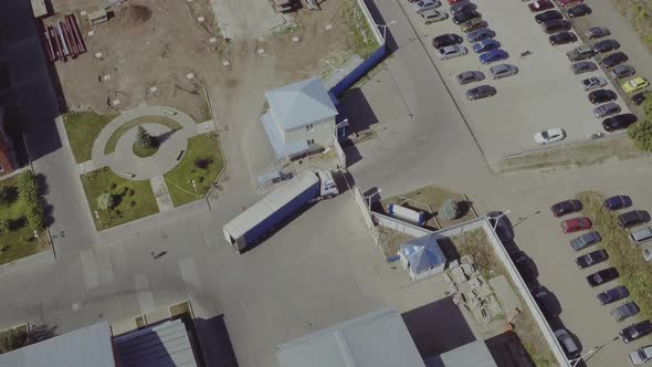 Aerial Top View of Ruck with Attached Semi Trailer Leaving Industrial Plant, Storage Building