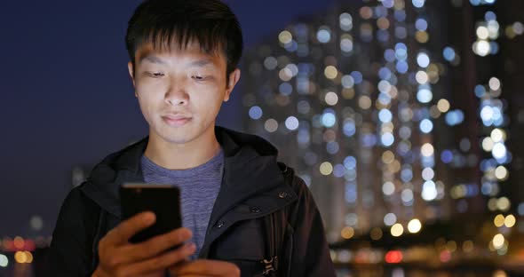 Asian man use of mobile phone in city in the evening