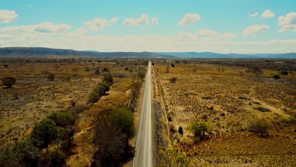 A rural road in the Brazilian countryside through drought stricken farmland - aerial view