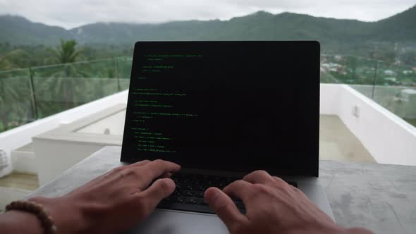 POV of Programmer Developer Freelancer Writes Green Code at a Laptop Outside the Office on the Reef