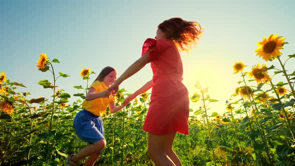 Mom and Daughter Have Fun in a Field of Sunflowers at Sunset