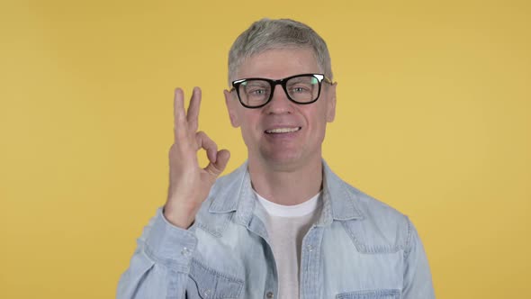 Okay Sign By Casual Senior Man on Yellow Background