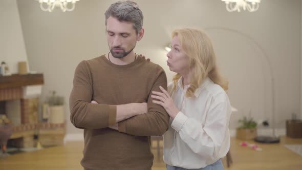 Senior Blond Caucasian Woman Calming Down Bearded Man with Gray Hair at Home