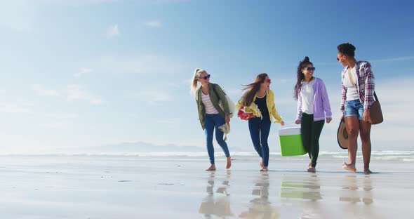 Happy group of diverse female friends having fun, walking along beach