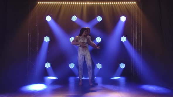 Young Couple Dancing Latin Music. Bachata, Merengue, Salsa. Shot in a Dark Studio with Neon Lights