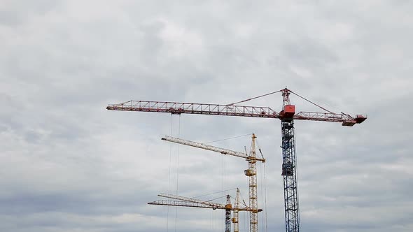 Cranes Working on Construction Site Under Grey Cloudy Sky on a Rainy Day Timelapse