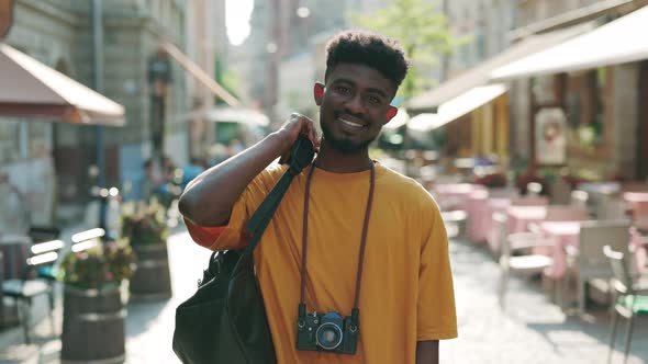 Happy African American Tourist in Casual Wear Standing on City Street Looking at Camera