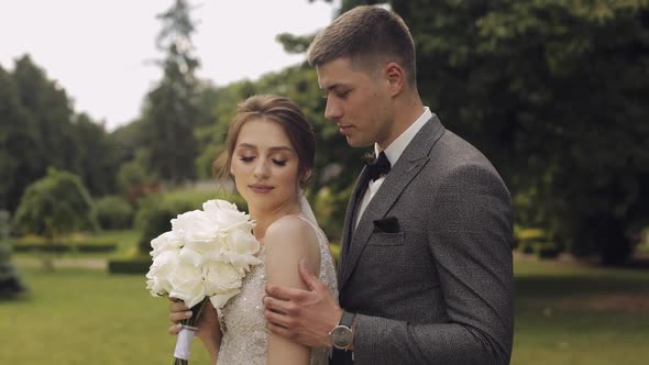 Newlyweds Caucasian Groom with Bride Walking Embracing Hugs in Park Wedding Couple