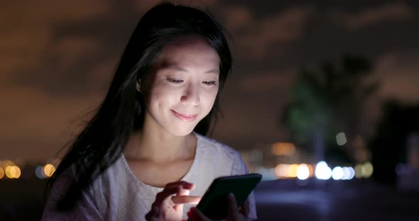 Woman Surfing Online on Cellphone at Night 