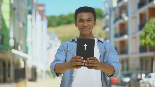 Happy African-American Boy Showing Holy Bible on Camera and Smiling, Religion