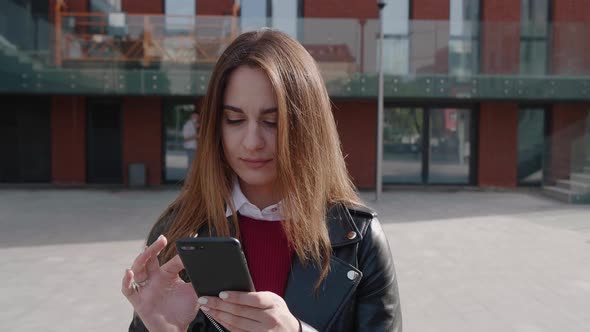 A Young Woman Surfing the Internet on Smartphone Flipping Good New and Smilling of the Business