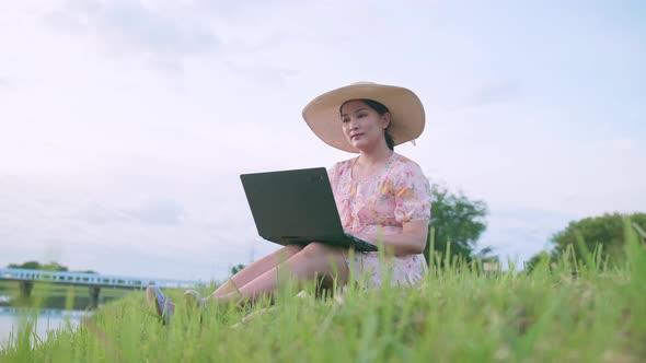 Freelance Asian woman using a notebook in the external nature area.