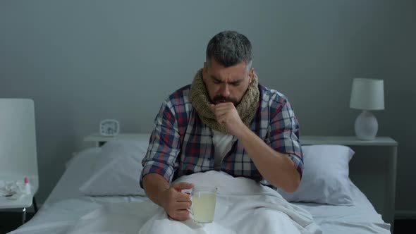 Sick Man Coughing in Bed, Drinking Antipyretic Tea to Treat Fever, Flu Epidemic