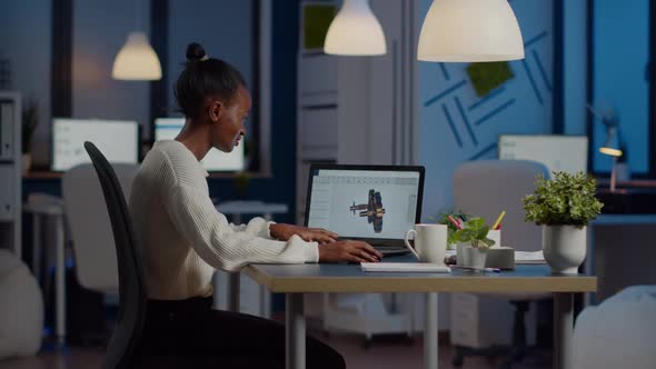 African Engineer Working Late at Night on a 3D Model of Industrial Gears