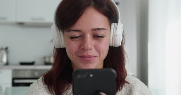 Young Smiling Girl in Headphones Using Mobile Phone and Smiling