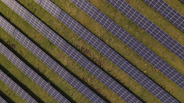 Gigantic solar farm on a lush green meadow. Rotating aerial top down view