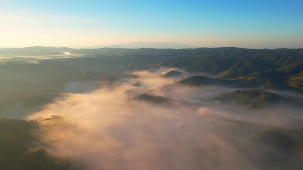 4K Aerial view from drone over mountains and sea of fog. Golden scenery at sunrise