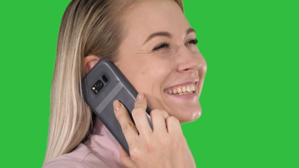 Smiling blonde talking on the phone on a Green Screen, Chroma Key.