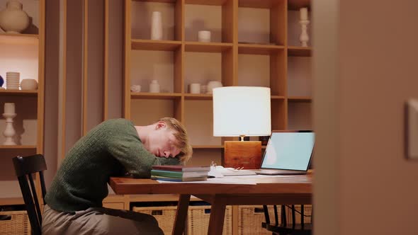 Guy Fell Asleep While Doing Homework at the Table Lying on Books Side View