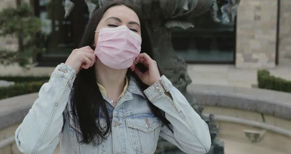 Happy Girl in Garden Undresses Medical Mask and Smiles at Camera with Relief