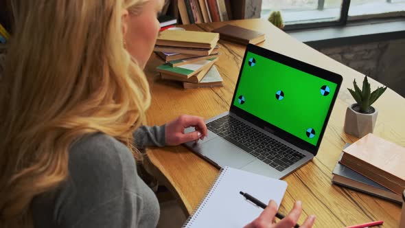 Over the Shoulder Shot of a Business Woman Working in Office Interior on a Laptop on Wooden Desk