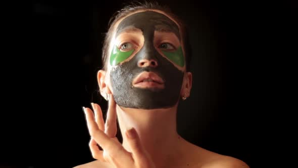 The Girl With A Cosmetic Face Mask On A Black Background