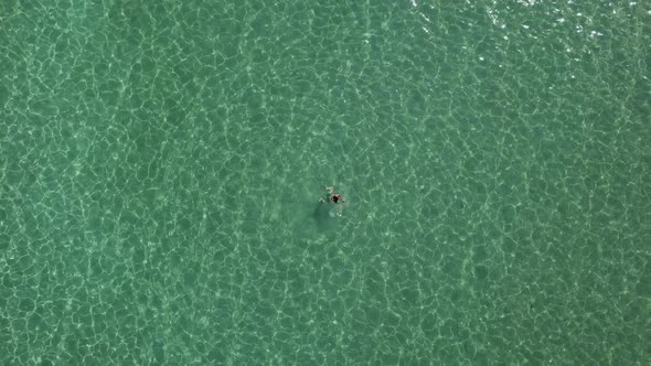 Female tourist floats and swims in the clear green waters of the Aegean Sea; Paros island, Greece; a