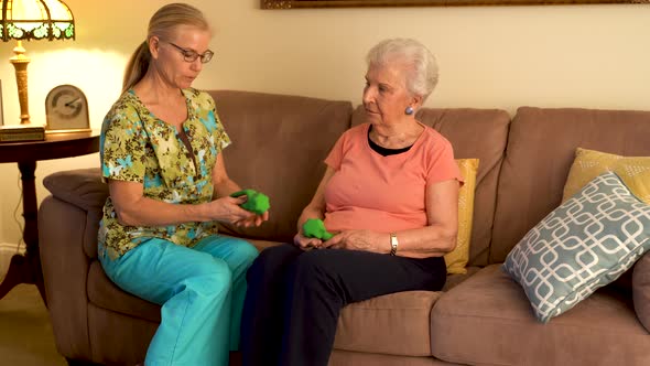 Physical therapist doing a home healthcare visit with an elderly woman showing her how to use weight