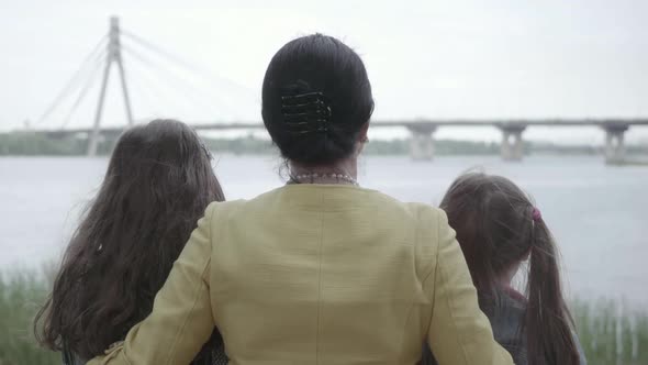 Pretty Grandmother Hugging Her Two Granddaughters Near Beautiful River