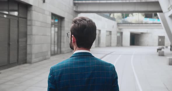 Back View on the Confided Businessman in Glasses Walking the Street at the Office Center