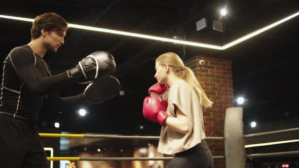 Angry Sport Woman Training with Coach at Gym. Fit Girl Fighting on Boxing Ring