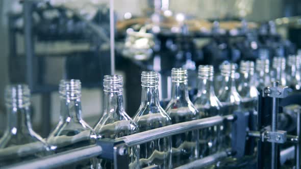 Glass Bottles Are Slowly Moving Along the Metal Conveyor