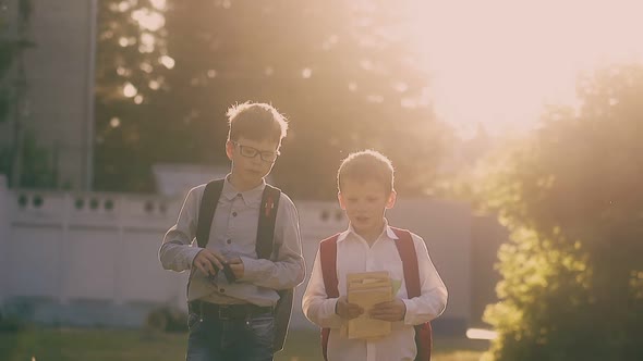 Kids in Shirts Silhouettes Walk Holding Books After Exam