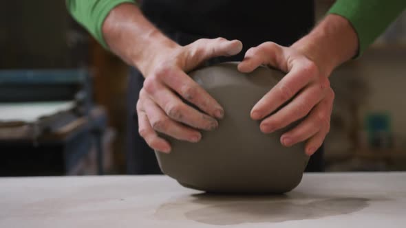 Close up view of male potter kneading the clay at pottery studio