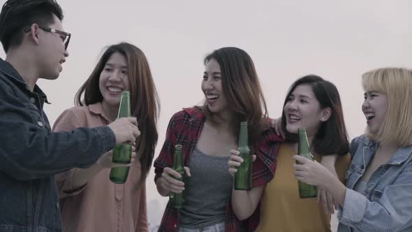 Group of young asian people dancing and raising their arms up played sunset on rooftop hanging out.