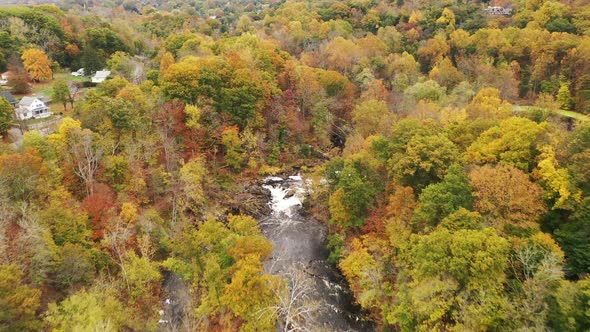 An aerial drone shot of the colorful fall foliage in upstate NY. The camera dolly in high over the t