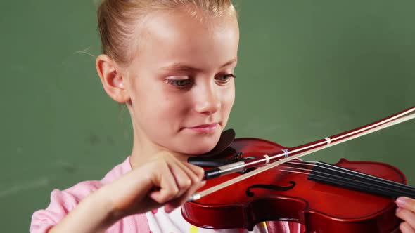 Schoolgirl playing violin in classroom at school